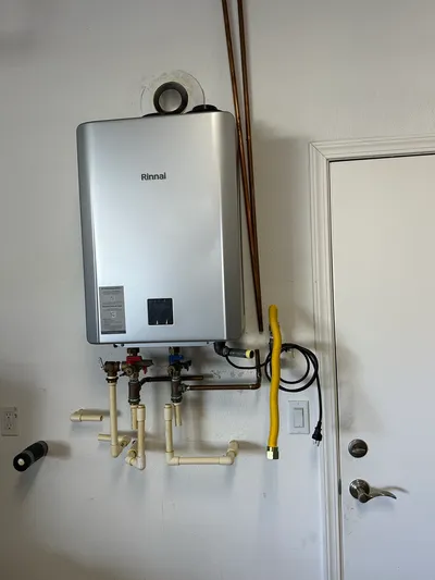 A wall-mounted Rinnai tankless water heater with copper supply lines and service isolation valves